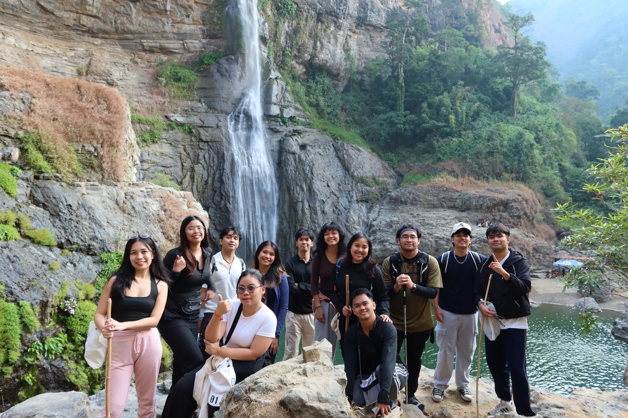 A group posing on the rocks beside a waterfall